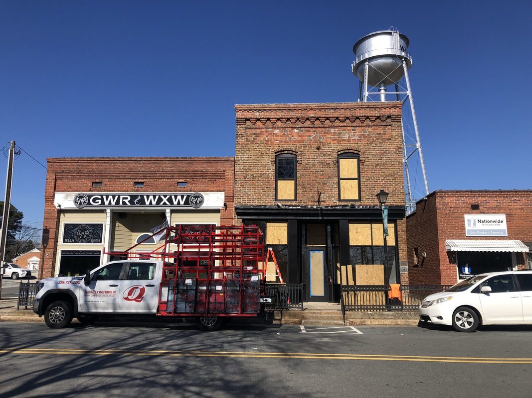 The storefront boarded up during the renovation, with a glass truck parked out front