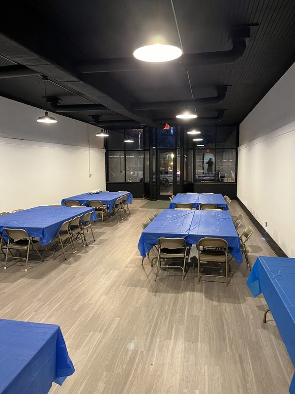 The restored first floor fellowship hall, with a black beadboard ceiling, new floors and pendant lights, looking toward the new storefront windows